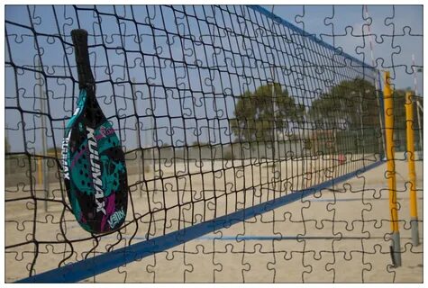 Jogador de beach tennis realizando um saque em quadra de areia com foco na técnica.