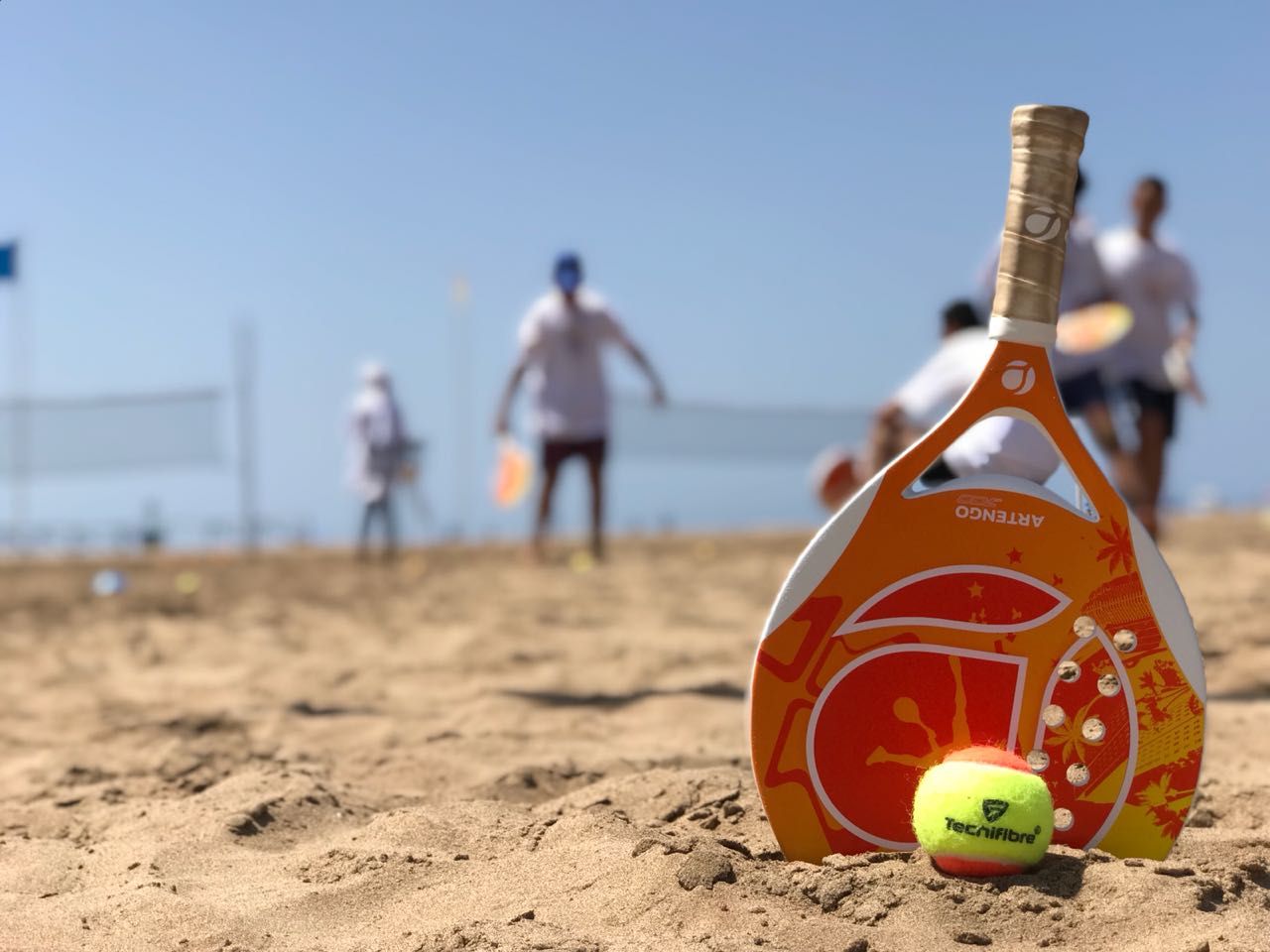 Jogador de beach tennis executando o split step em uma quadra de areia.