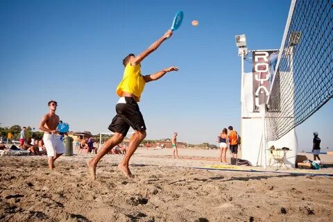 Jogador de beach tennis praticando posicionamento vertical com cones em uma quadra de areia.