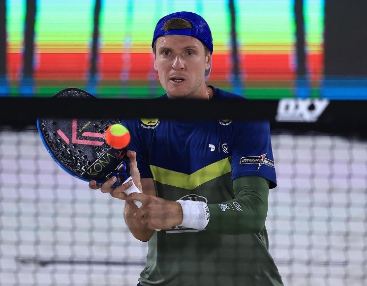 André Baran jogando beach tennis em uma quadra de areia, representando sua carreira e desafios.