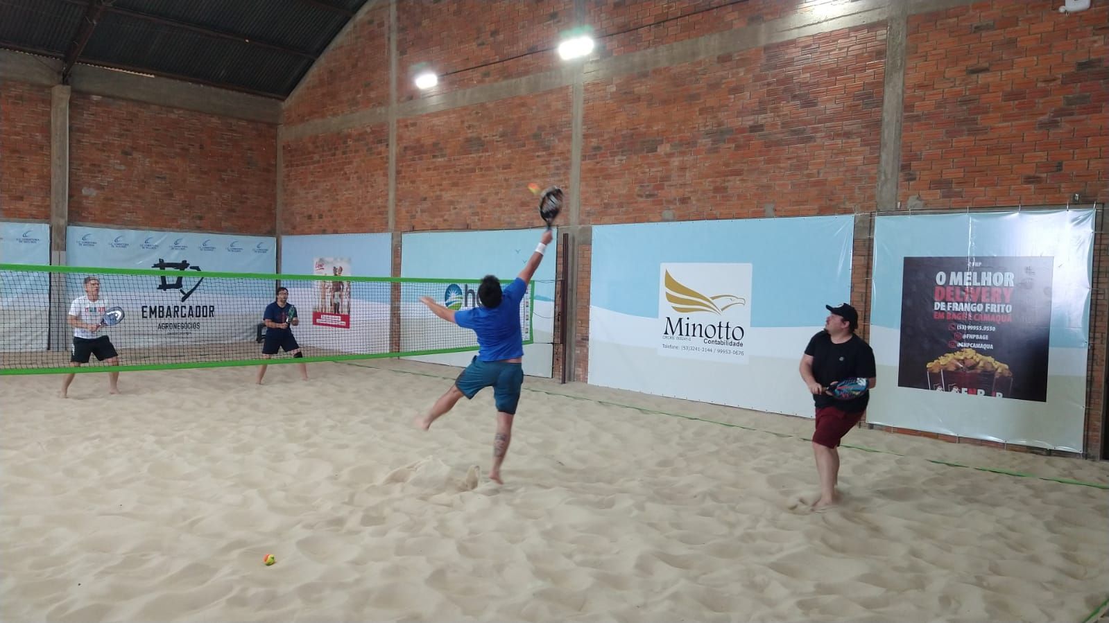 Atletas competindo na terceira etapa da Liga Bageense de Beach Tennis em quadras de areia.