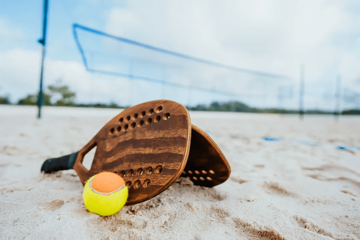 Atletas competindo no Macena Open na Praia de Pajuçara, Maceió, com uma grande estrutura montada para o evento.