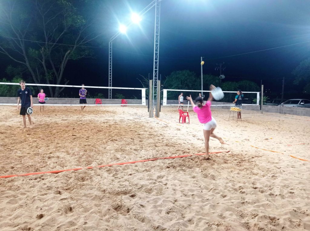 Quadra de beach tennis na Arena 7, com jogadores se divertindo e aproveitando o dia.