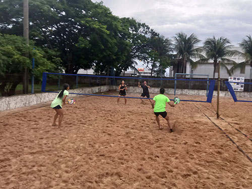 Atletas competindo em um torneio de beach tennis em Água Boa, enfrentando chuvas e mostrando determinação.