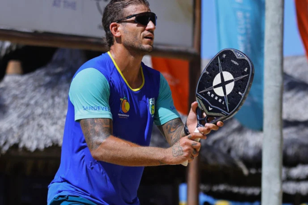 Rafael Moura jogando beach tennis em uma quadra de areia, representando Minas Gerais.