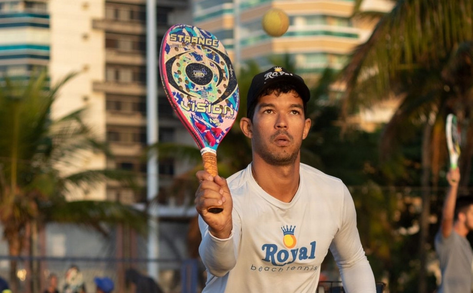 Atletas competindo no Mundial de Beach Tennis na Praia de Camburi, Vitória, com areia e público animado.