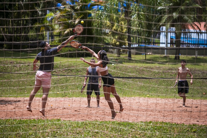 Participantes competindo no torneio de beach tennis no Sesc Thermas, com quadra de areia ao fundo.