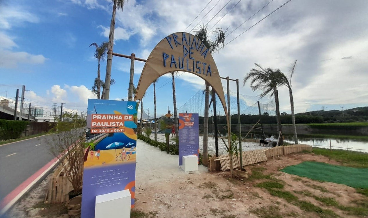 Prainha de Paulista com areia e cadeiras vazias, refletindo a baixa adesão do público e a poluição nas margens do Rio Pinheiros.