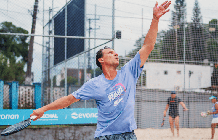 Atletas jogando beach tennis em uma quadra de areia durante torneio em Blumenau.