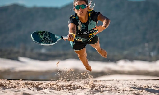 Jogadores de beach tennis em quadra de areia durante uma competição.