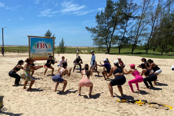 Famílias participando de atividades esportivas na praia durante o Esporte Verão em Santa Clara.