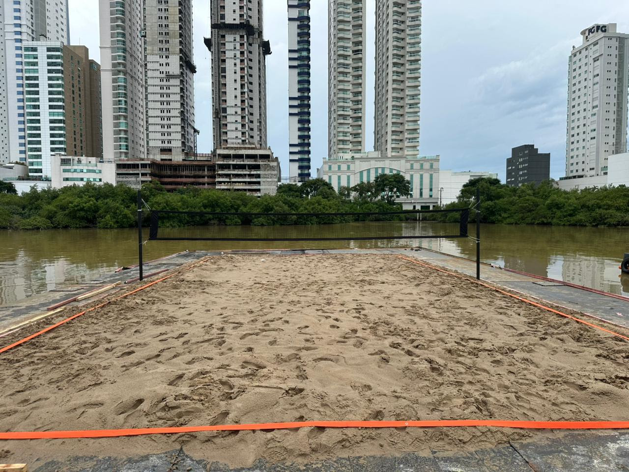 Quadra flutuante de beach tennis na Praia Central de Balneário Camboriú com atletas em ação.