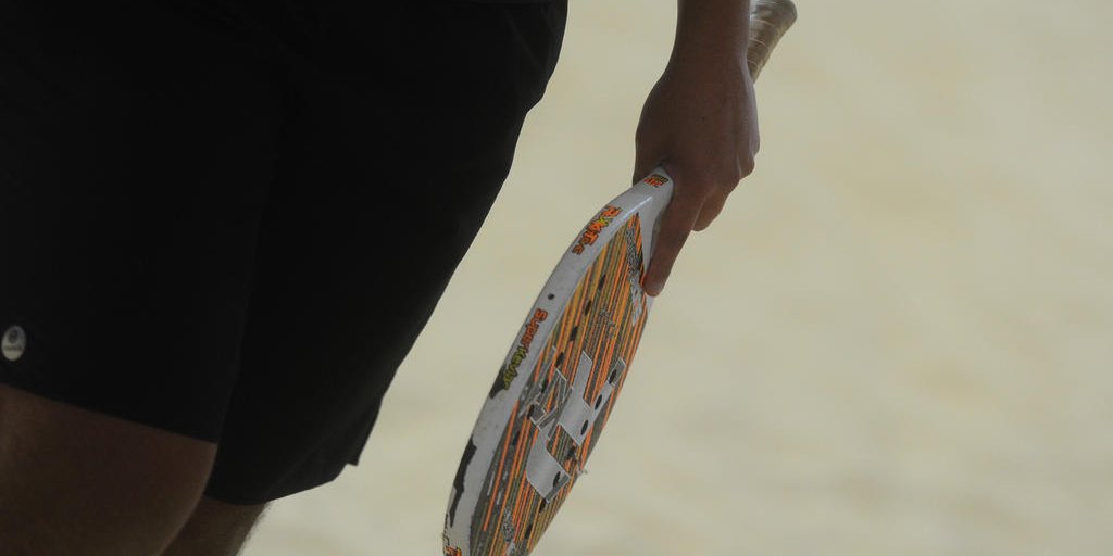 Atletas de beach tennis competindo em uma quadra de areia, refletindo sobre desafios e preparação.