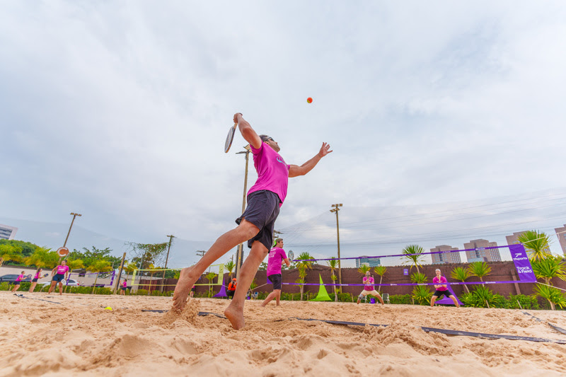 Competição de beach tennis em Guarapari com atletas em ação na areia.