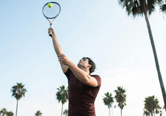 Jogadores de beach tennis em ação, destacando a movimentação rápida e a superfície arenosa que podem causar lesões.