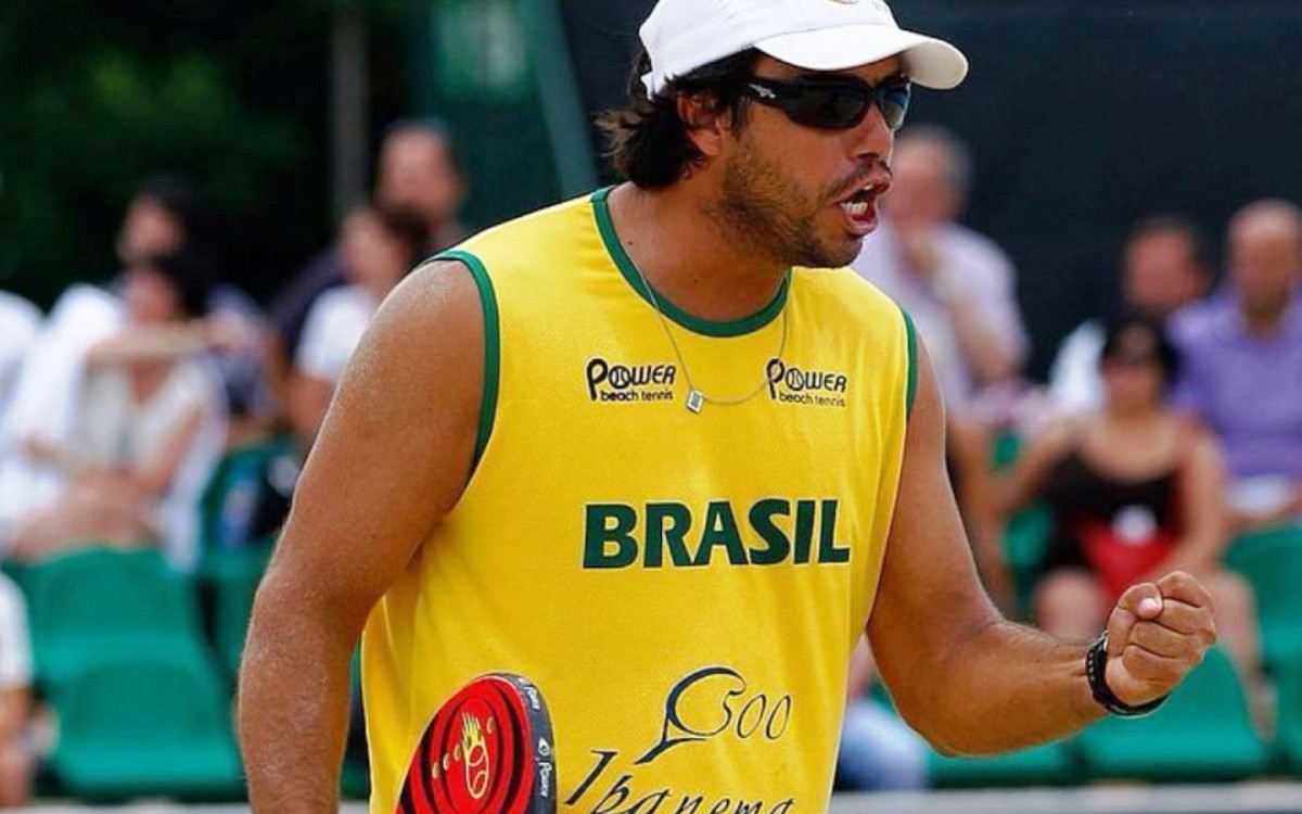 Guilherme Prata ensinando técnicas de beach tennis em uma clínica na praia.
