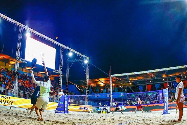 Praticantes de beach tennis jogando em uma quadra ao ar livre, destacando a socialização e atividade física.