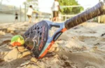 Jogadores de beach tênis se divertindo em uma quadra de areia sob o sol.