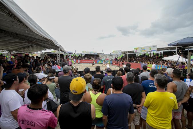 Jogadores de beach tennis competindo na Arena Portos do Paraná, com quadras de areia ao fundo.