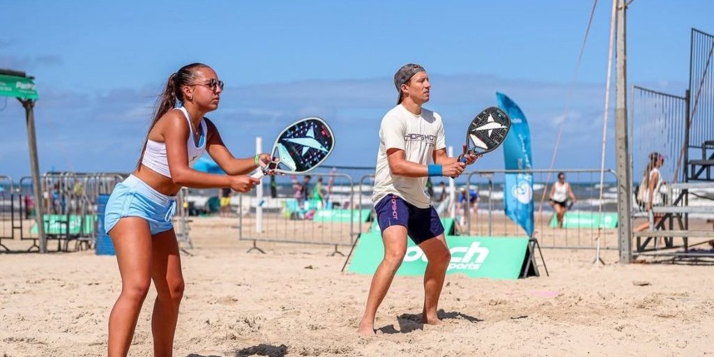 Atletas competindo no Atlântida Open de Beach Tennis em Xangri-lá, com quadras montadas à beira-mar.