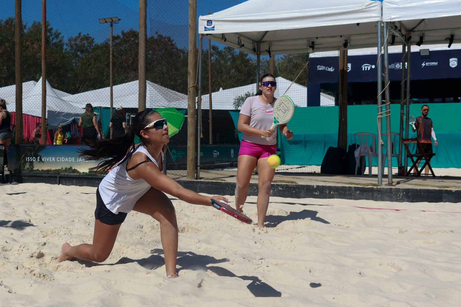 Atletas competindo no World Tour BT 400 de Beach Tennis em Cuiabá, com quadras de areia e público animado.