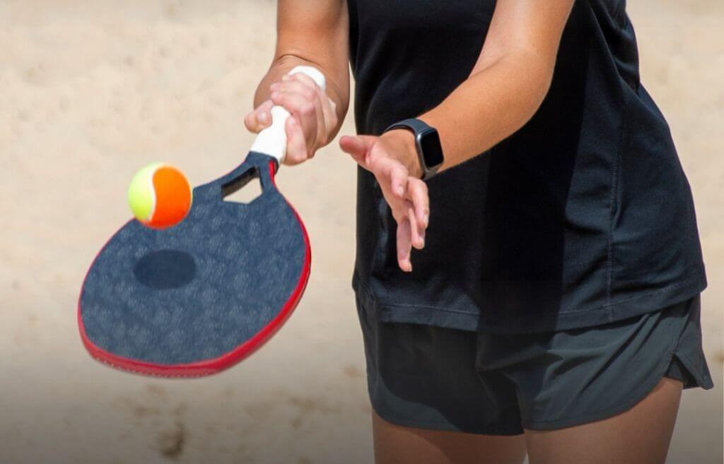 Atletas competindo no Campeonato de Beach Tennis em Campinas do Sul, com quadras de areia e público animado.