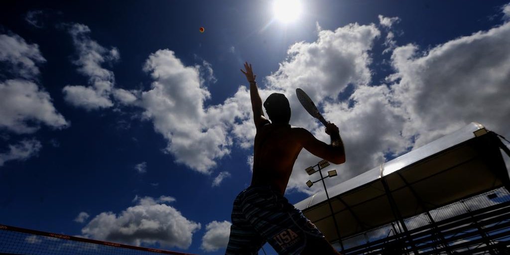 Atleta de beach tennis concentrado antes de um torneio, aplicando técnicas de controle emocional.