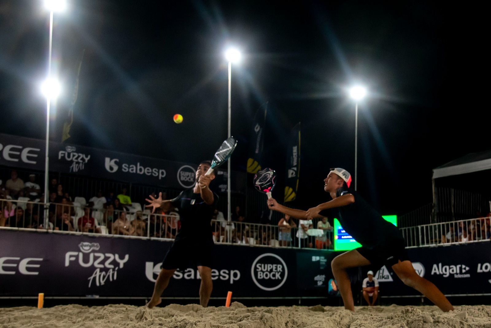 Atletas brasileiros celebrando vitória no torneio de beach tennis no Guarujá.