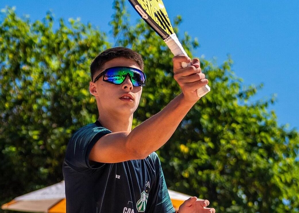 Atleta de beach tennis levantando o troféu após vencer a 6ª etapa do Circuito Verão Paulista.