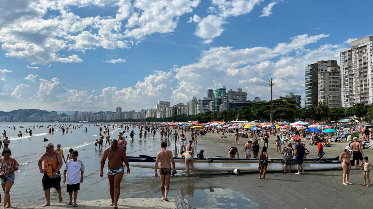 Praia de Santos com ambulantes, praticantes de futevôlei e beach tennis.