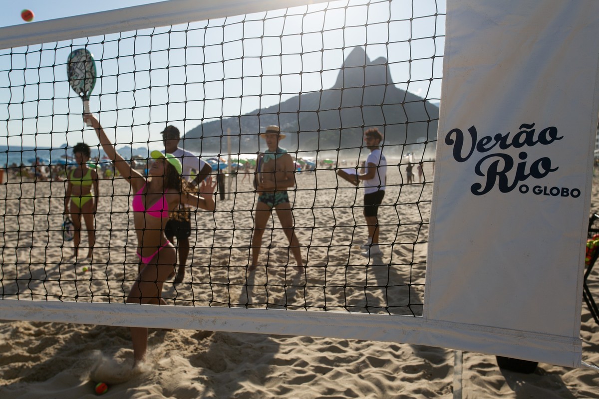 Jogador de beach tennis praticando um saque em uma quadra de areia.