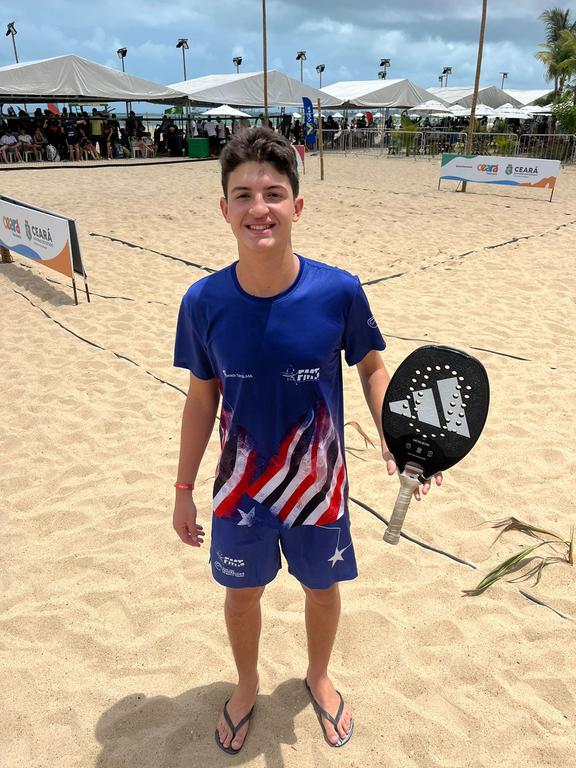 Augusto Neto jogando beach tennis em uma quadra de areia.