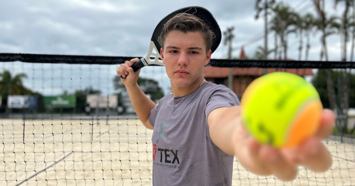 André Caetano, jovem atleta de beach tennis, em ação durante uma competição na praia.